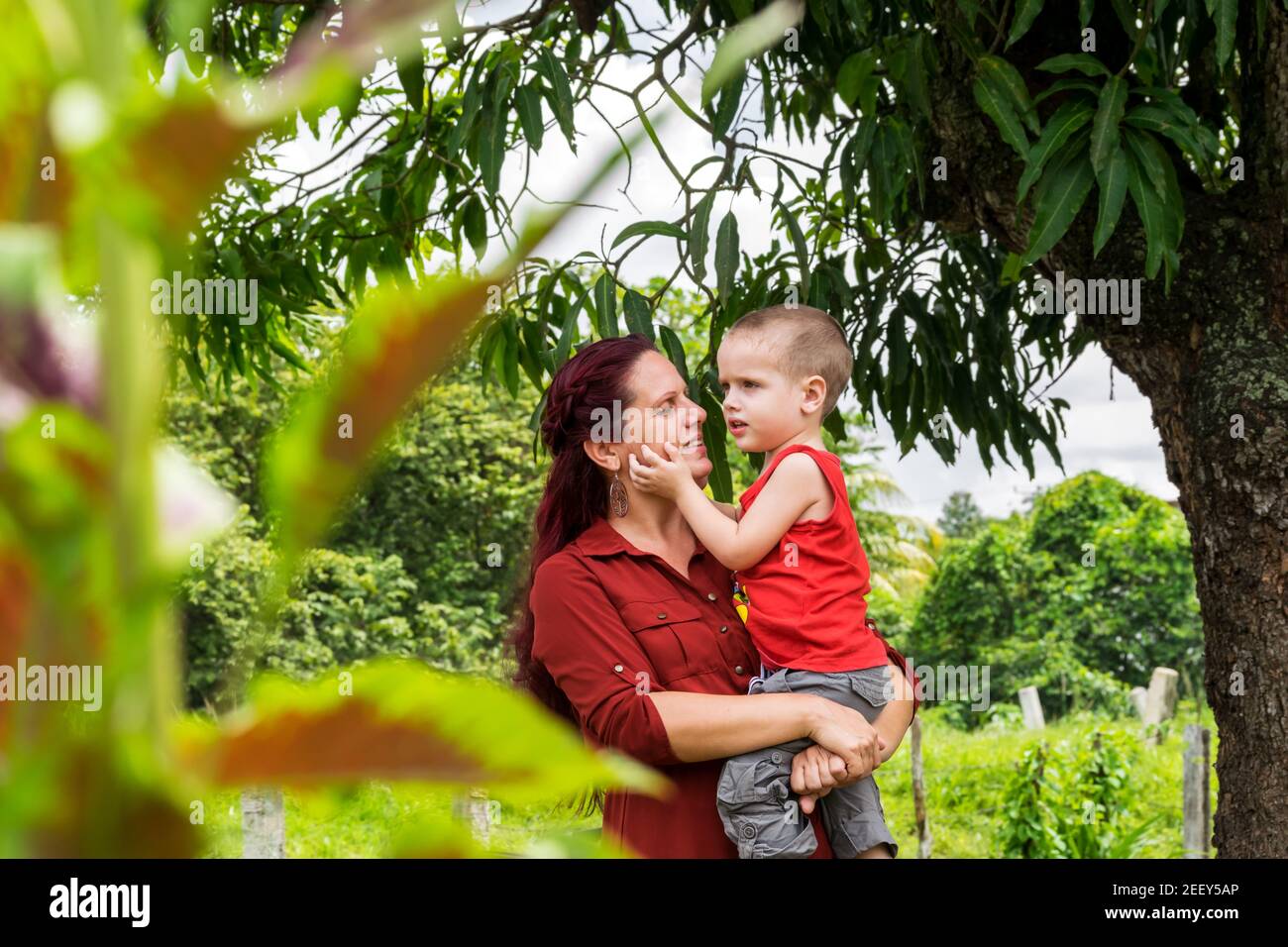 Cuban mother holding her three-year-old son in her arms while he is cherishing his mother´s face with his hand Stock Photo