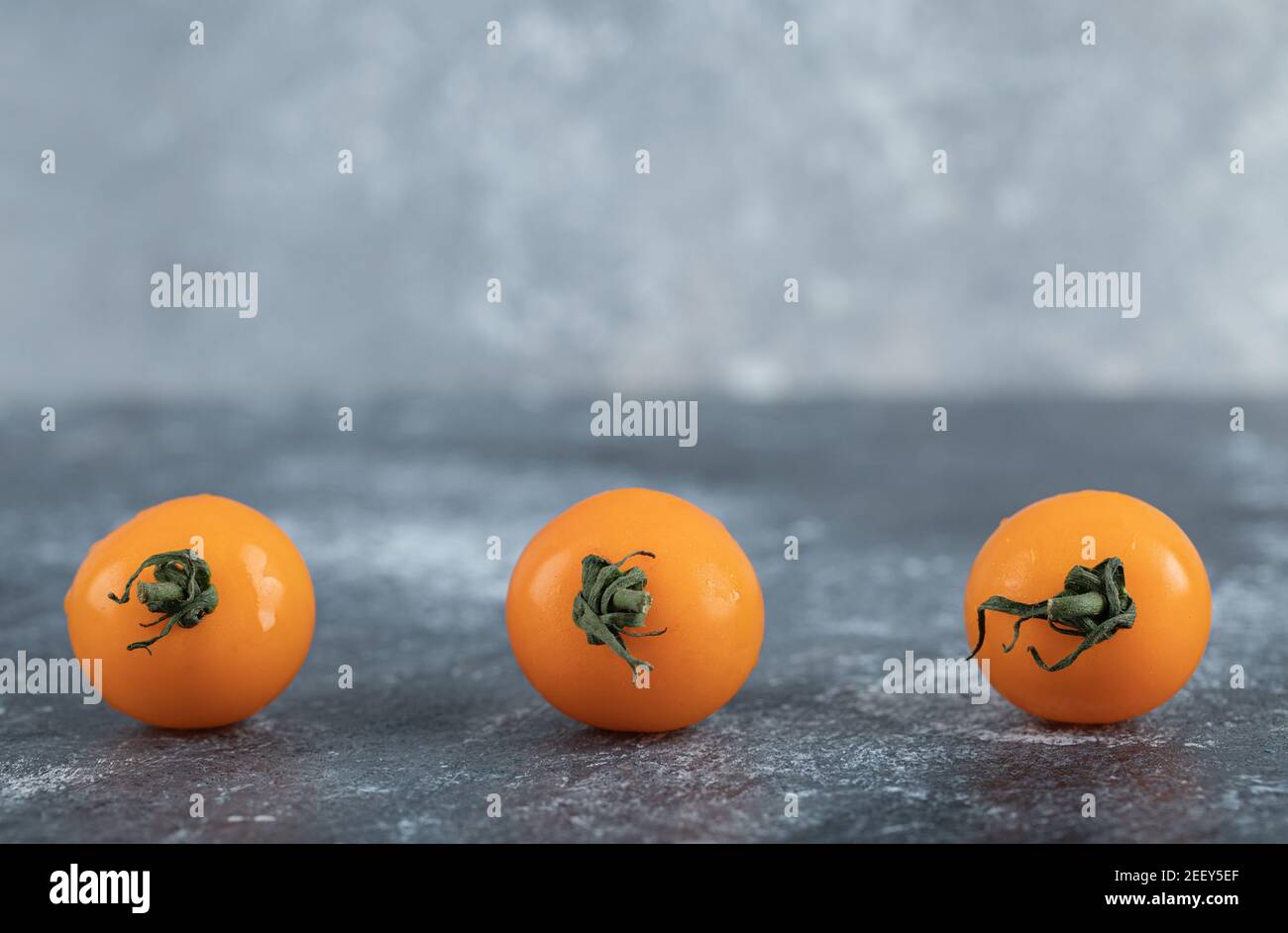Three separated yellow cherry tomatoes on board Stock Photo