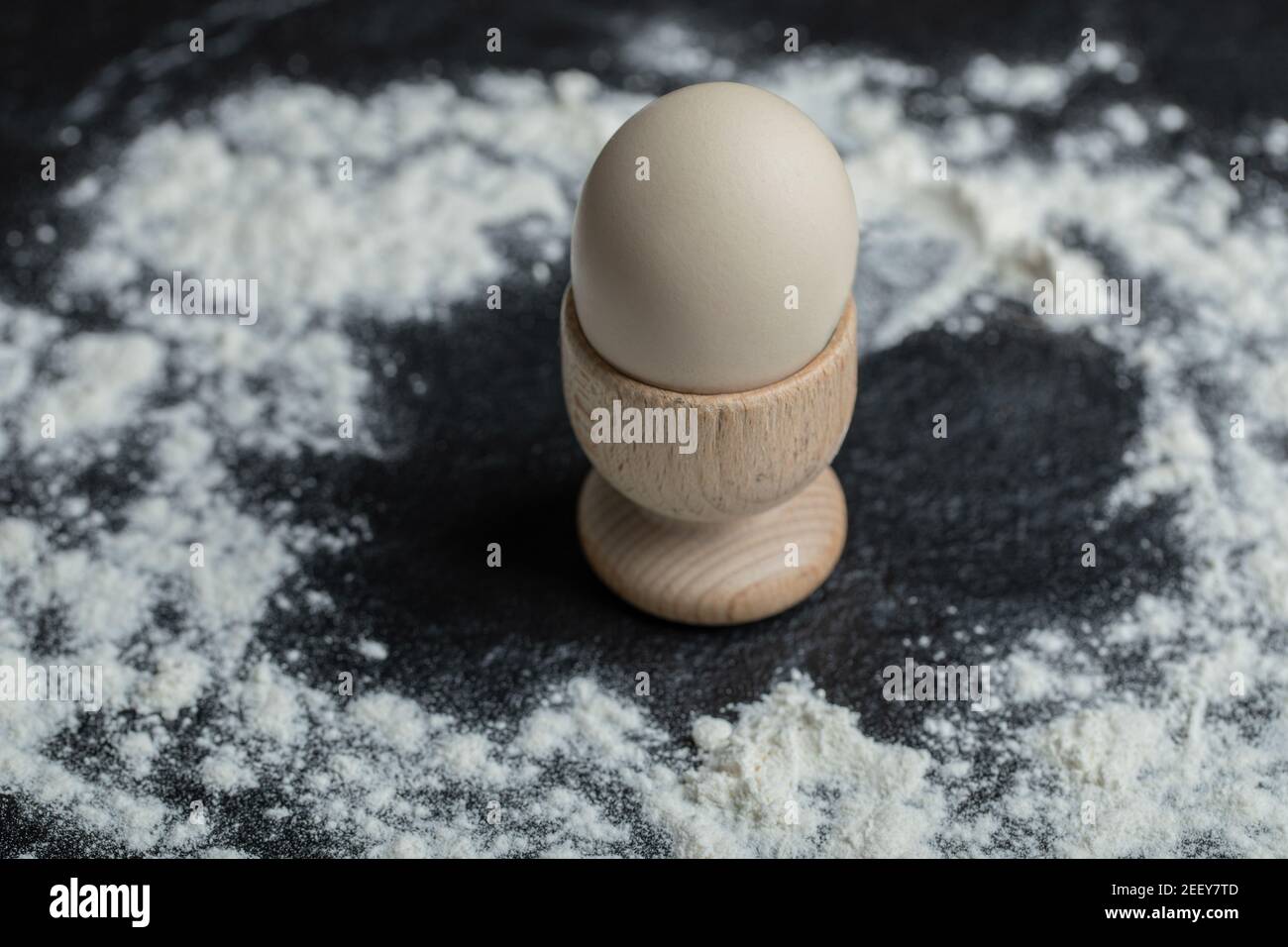 White egg in egg cup on floury background Stock Photo