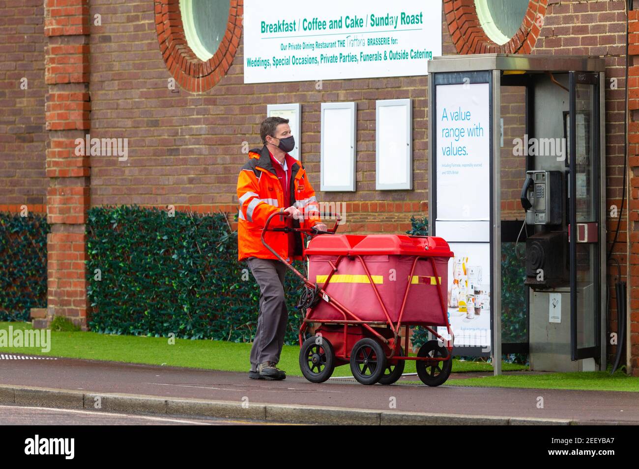 Royal mail lockdown postman wearing facemask with trolley, uk Stock Photo