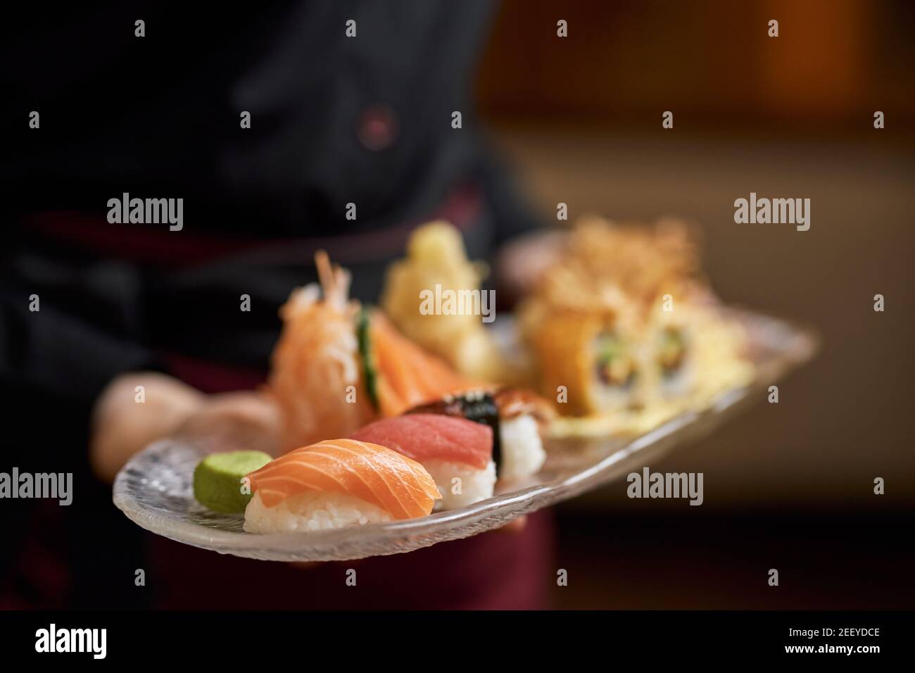 Close-up photo of plate with flavourful sushi and sashimi being carried by a waitress Stock Photo