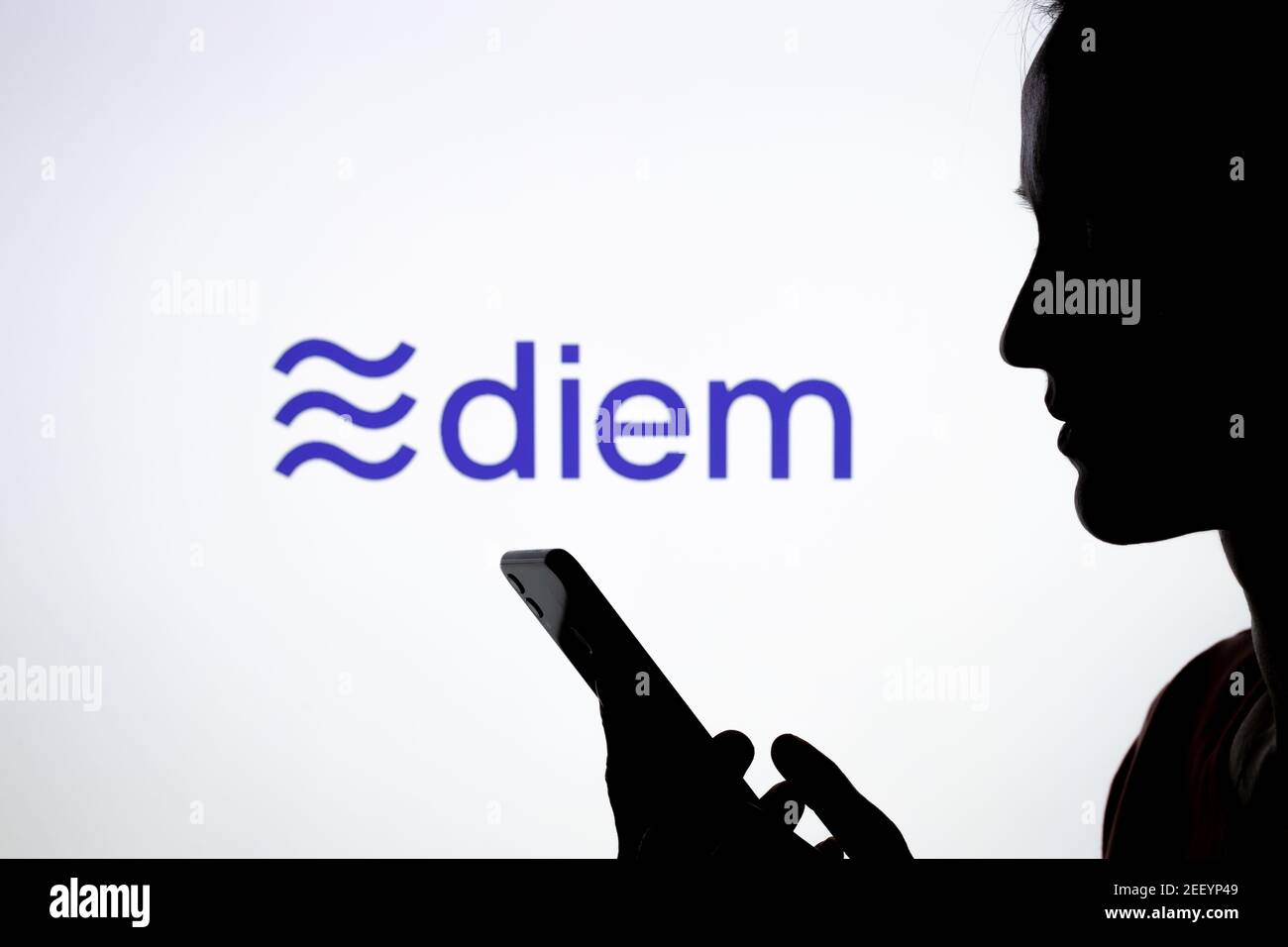 Silhouette of a girl with smartphone and Facebook Diem cryptocurrency logo on the blurred screen. Real photo, not a montage, no edit in post. Stafford Stock Photo