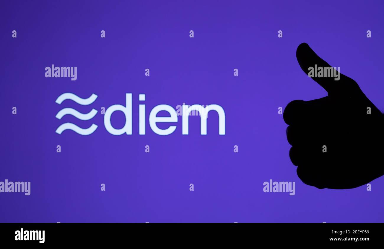 Silhouette of hand showing thumb up and Facebook Diem crypto coin logo on the large blurred screen. Real photo, not a montage, no edit in post. Staffo Stock Photo