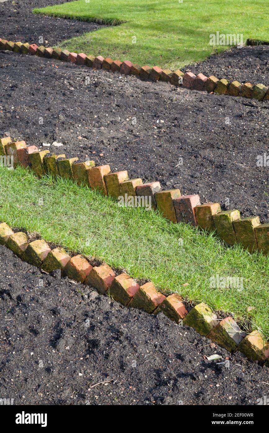 Preparing a new empty flowerbed in a UK garden with sawtooth brick edging Stock Photo