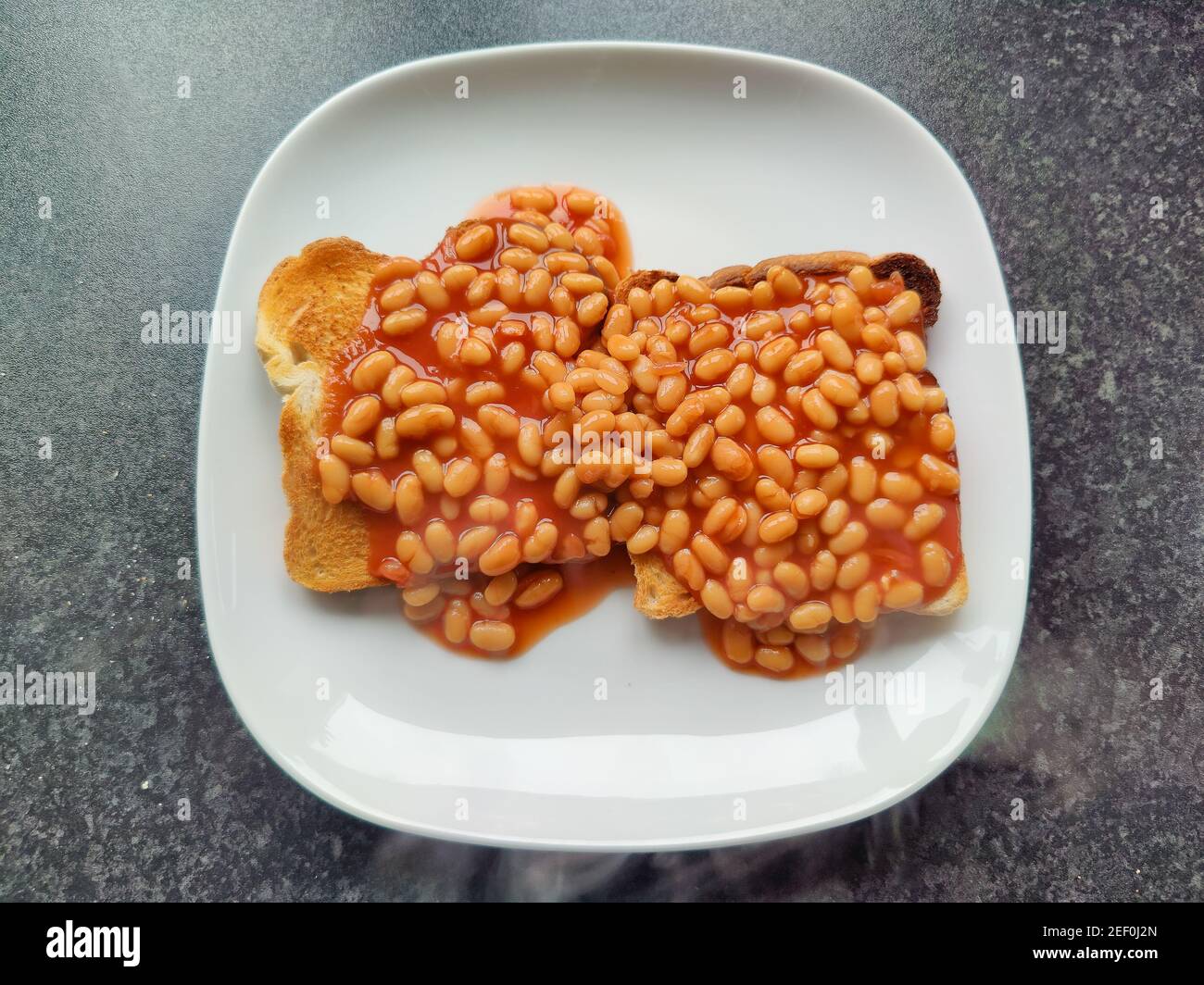 Baked beans on toast on a white plate Stock Photo