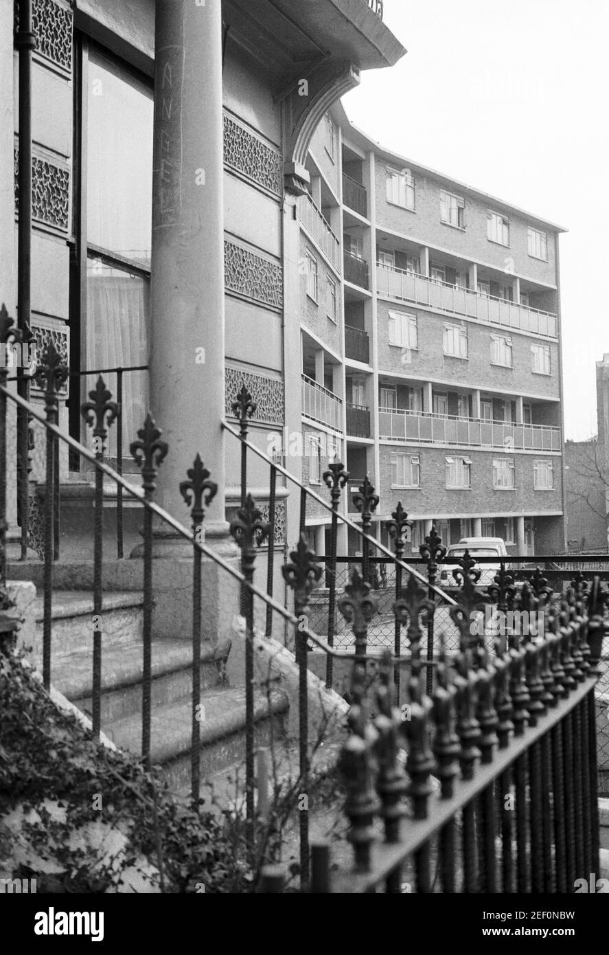 UK, West London, Notting Hill, 1973. Rundown & dilapidated large four-story houses are starting to be restored and redecorated. No.227 Westbourne Park Road & modern block of flats the other side of Powis Gardens. 'ANGEL' Graffiti on the house pillar. Stock Photo