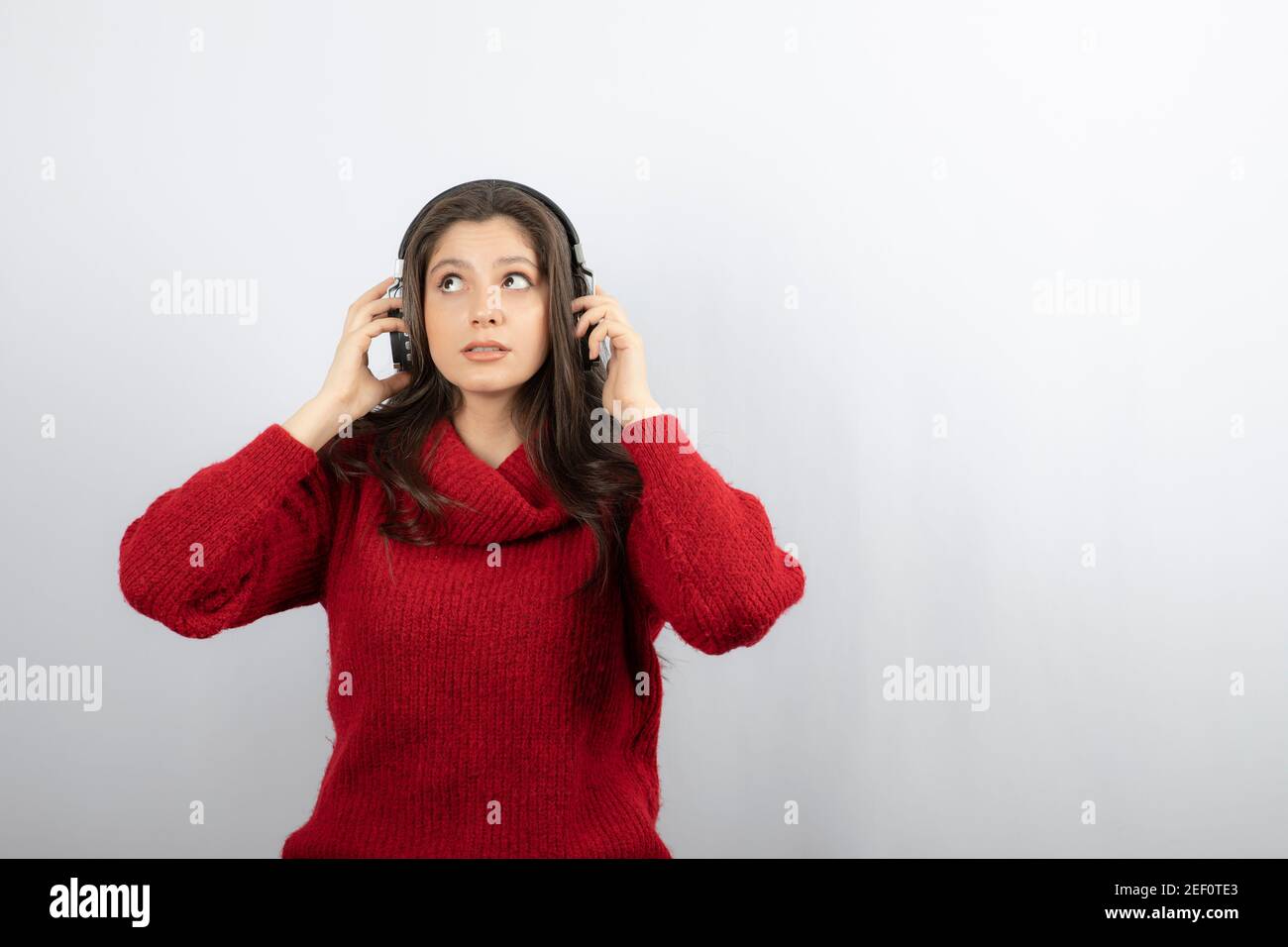 Photo of a young woman in red sweater wearing headphones Stock Photo