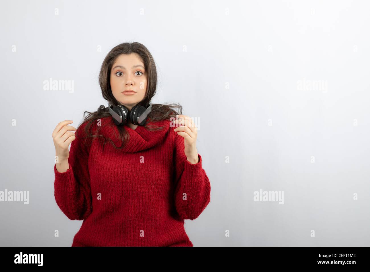 Photo of a young woman in red sweater wearing headphones on neck Stock Photo