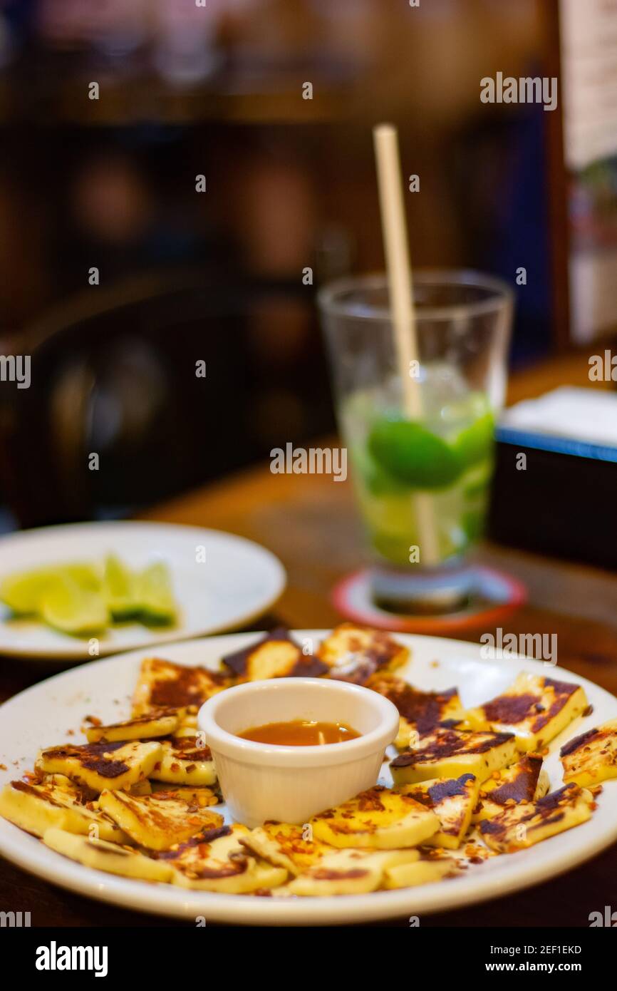 RIO DE JANEIRO, BRAZIL - JANUARY 3, 2020: Close up of tray with traditional grilled cheese, known as 'Queijo Coalho' with a caipirinha cocktail in the Stock Photo