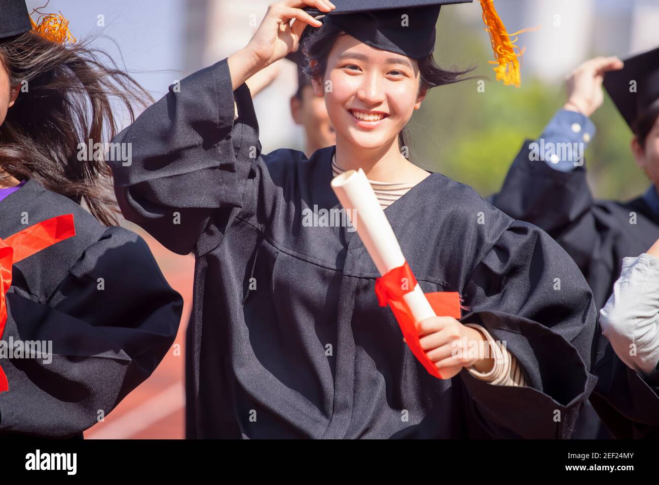 beautiful asian graduation student girl  holding diploma and running on the stadium at school Stock Photo
