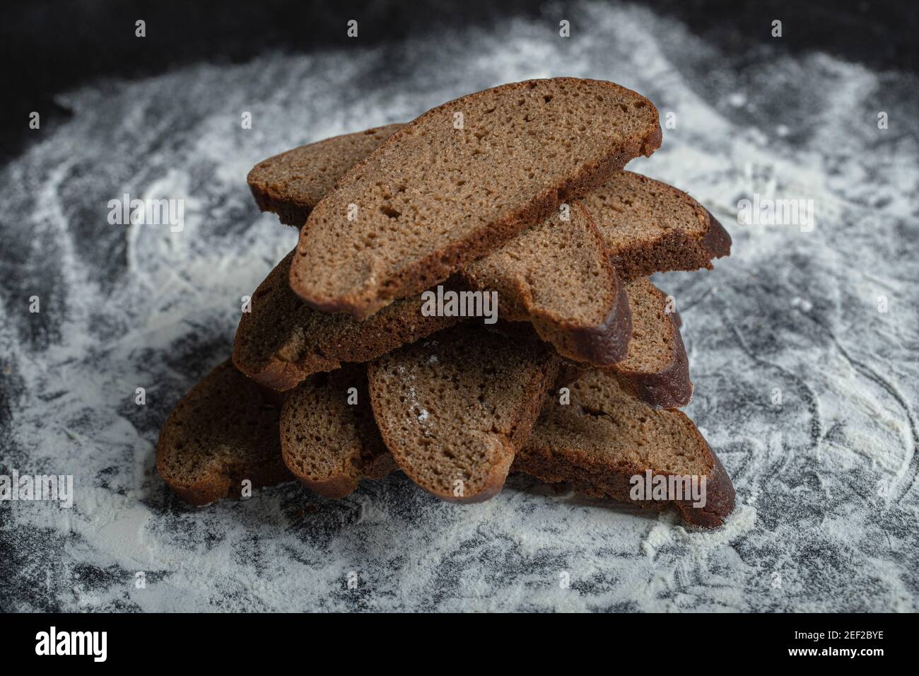 Freshly baked Brown bread slices on white flour background Stock Photo