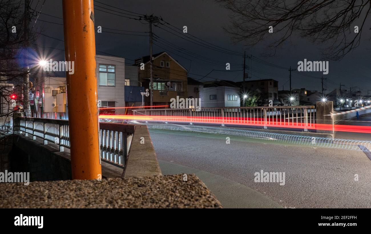 A light trail image of a car crossing a bridge at night in suburban Tokyo. Stock Photo