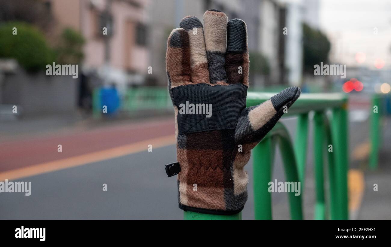 A glove sits on a post next to a busy road in Tokyo, Japan. Stock Photo
