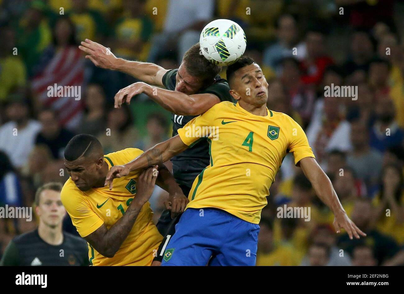 2016 Rio Olympics - Soccer - Final - Men's Football Tournament Gold Medal Match Brazil vs Germany - Maracana - Rio de Janeiro, Brazil - 20/08/2016.  Nils Petersen (GER) (C) of Germany collides with Walace (BRA) and his compatriot Marquinhos (R) in their gold medal men's football match.  REUTERS/Bruno Kelly  FOR EDITORIAL USE ONLY. NOT FOR SALE FOR MARKETING OR ADVERTISING CAMPAIGNS.   Picture Supplied by Action Images Stock Photo