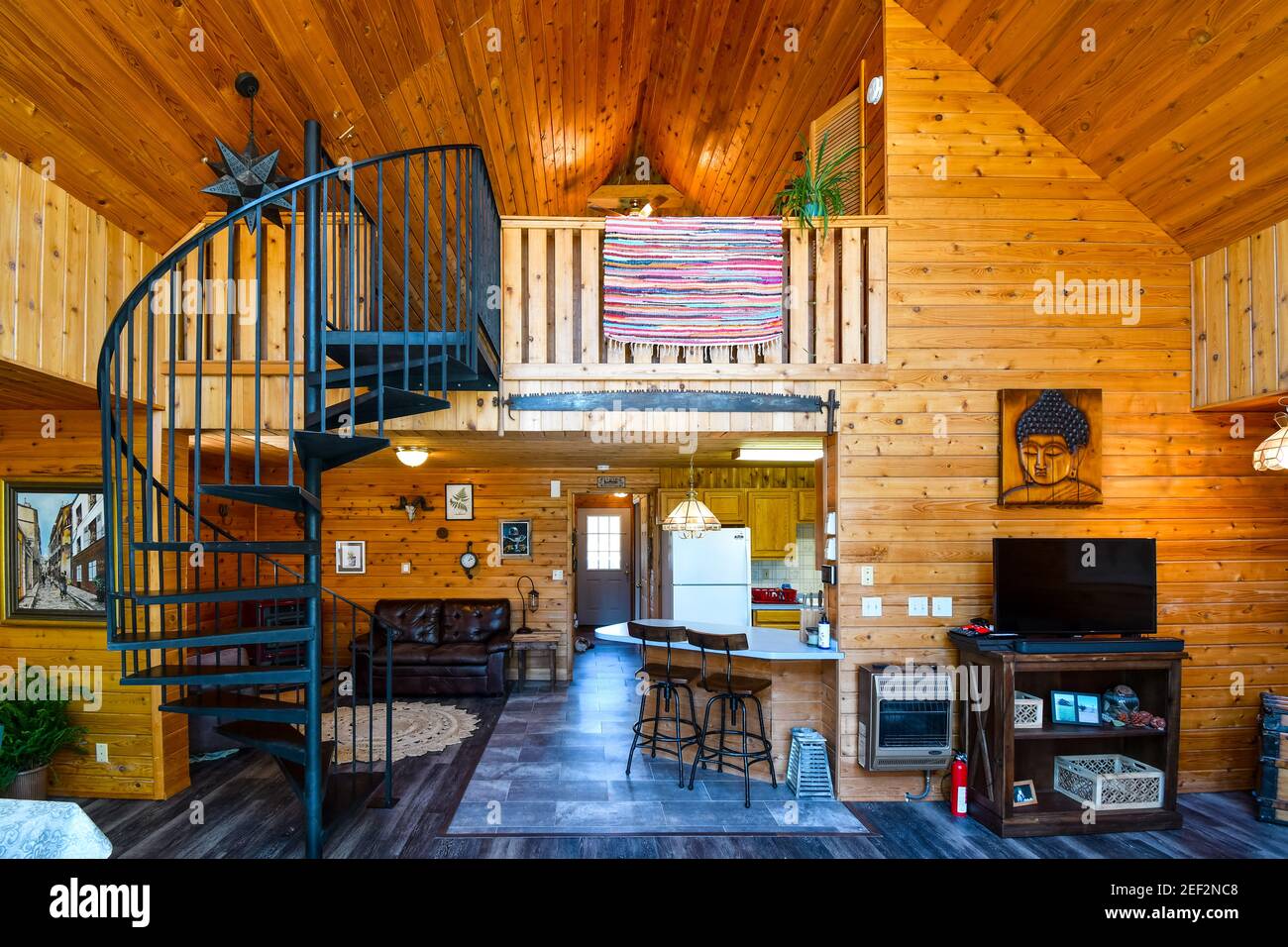Interior view of an upscale rustic log home with wooden cedar planks, loft and spiral staircase. Stock Photo