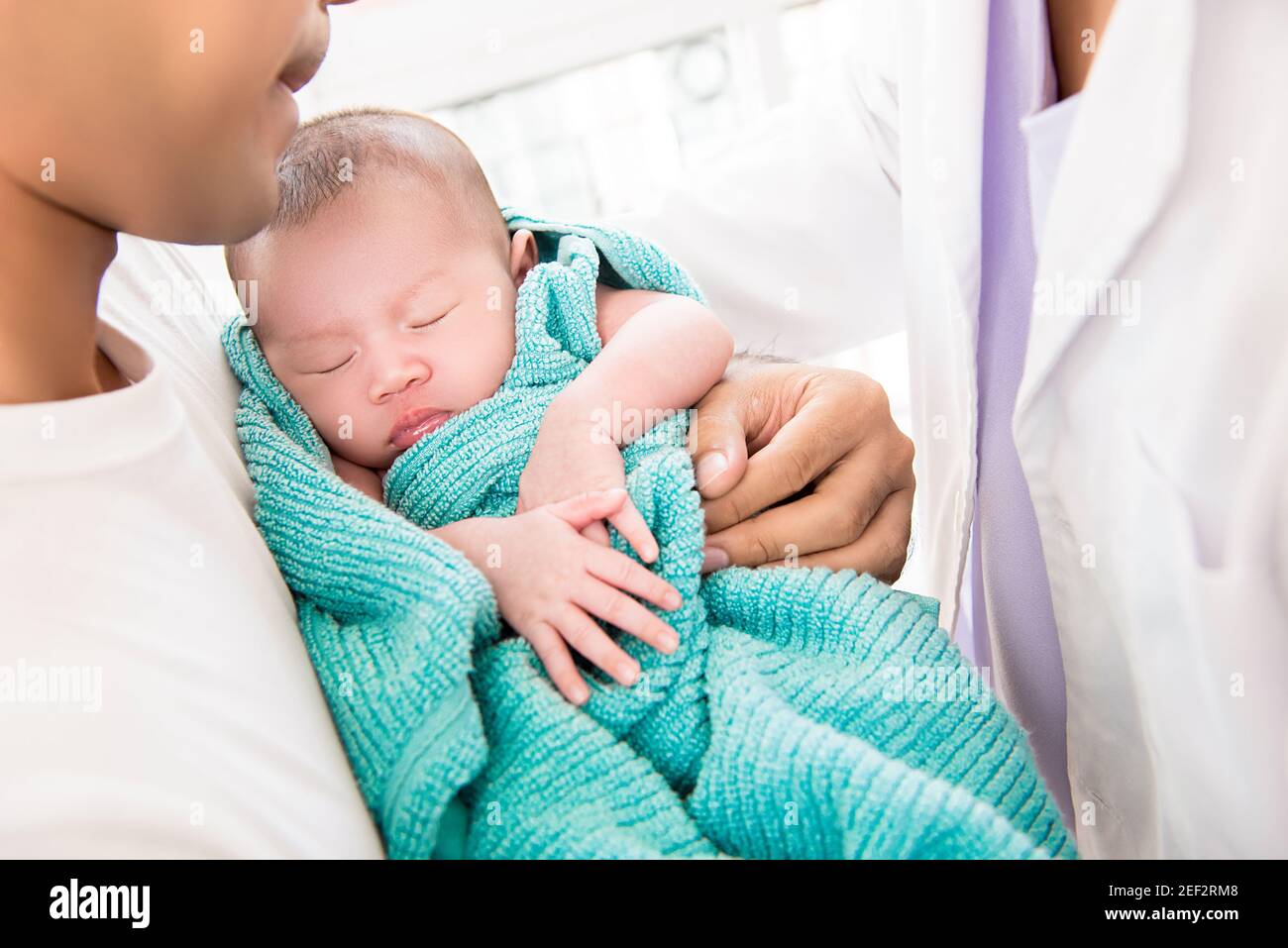 Doctor gently putting sleeping newborn baby into father arms Stock Photo