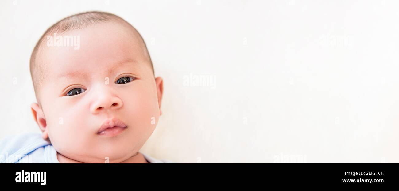 Face of cute newborn baby lying on white sheet - panoramic banner with copy space Stock Photo