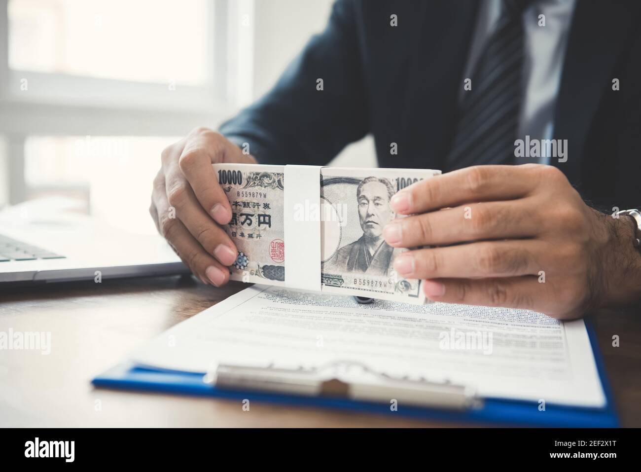 Businessman holding money, Japanese yen banknotes, on working table Stock Photo