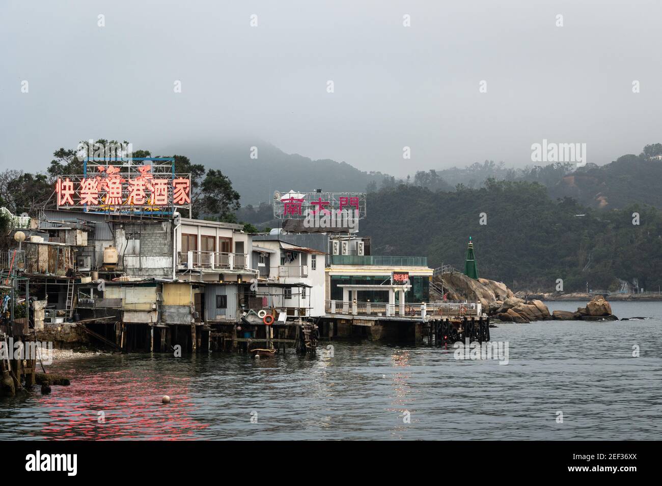 Lei Yue Mun, Hong Kong - March 15 2019: The seafood restaurants signs of the popular fishing village illuminate the water in Kowloon with the lighthou Stock Photo