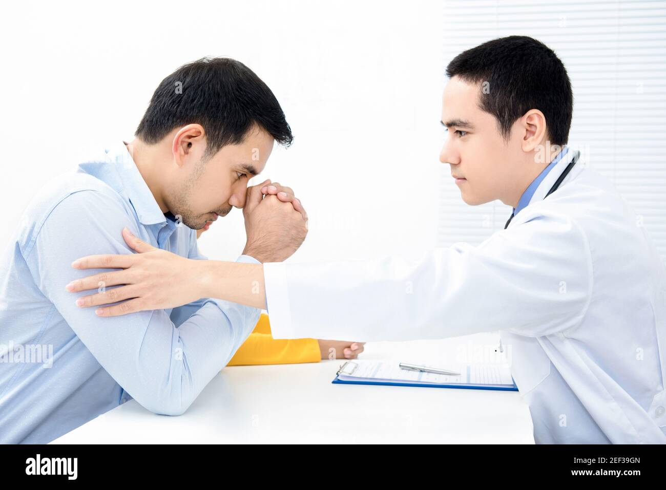 Doctor touching and   comforting depressed male patient Stock Photo