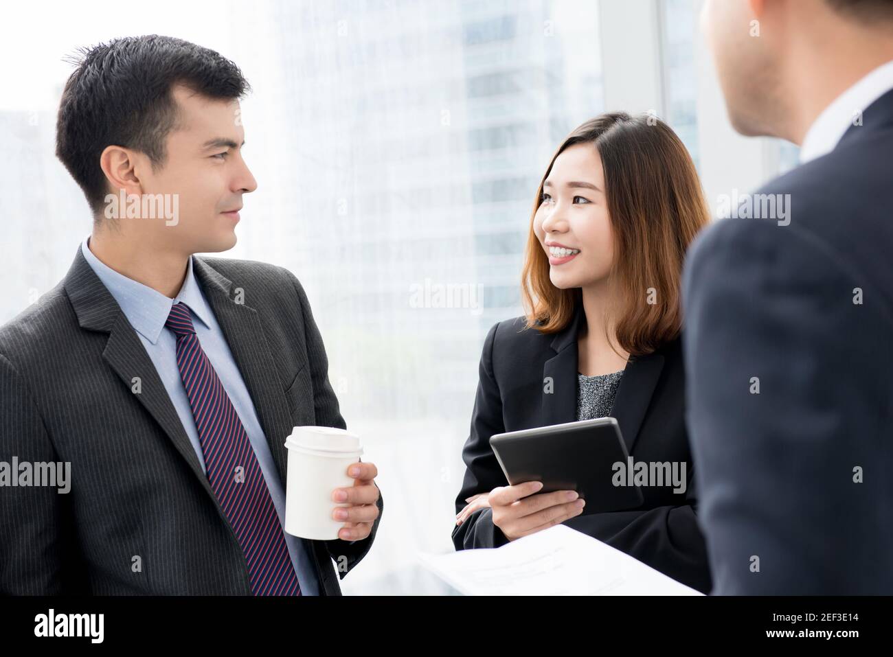 Business colleagues chatting in office building hallway Stock Photo - Alamy