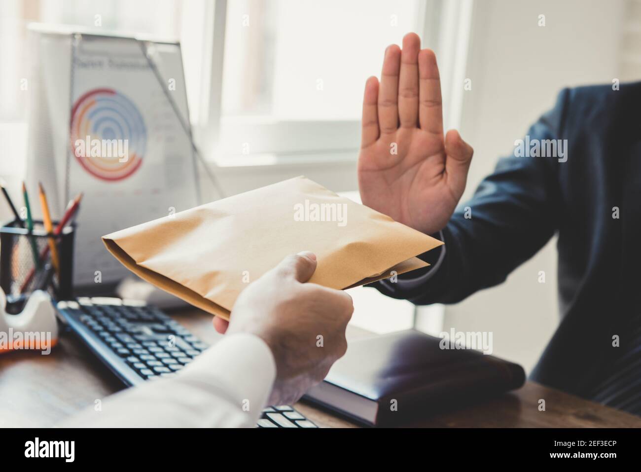 Businessman rejecting money (in the envelope) offering from his partner - anti bribery and corruption concepts Stock Photo
