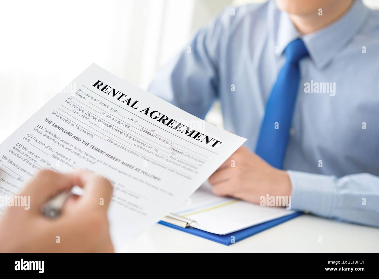 A man reading rental agreement document, about to fill and sign Stock Photo