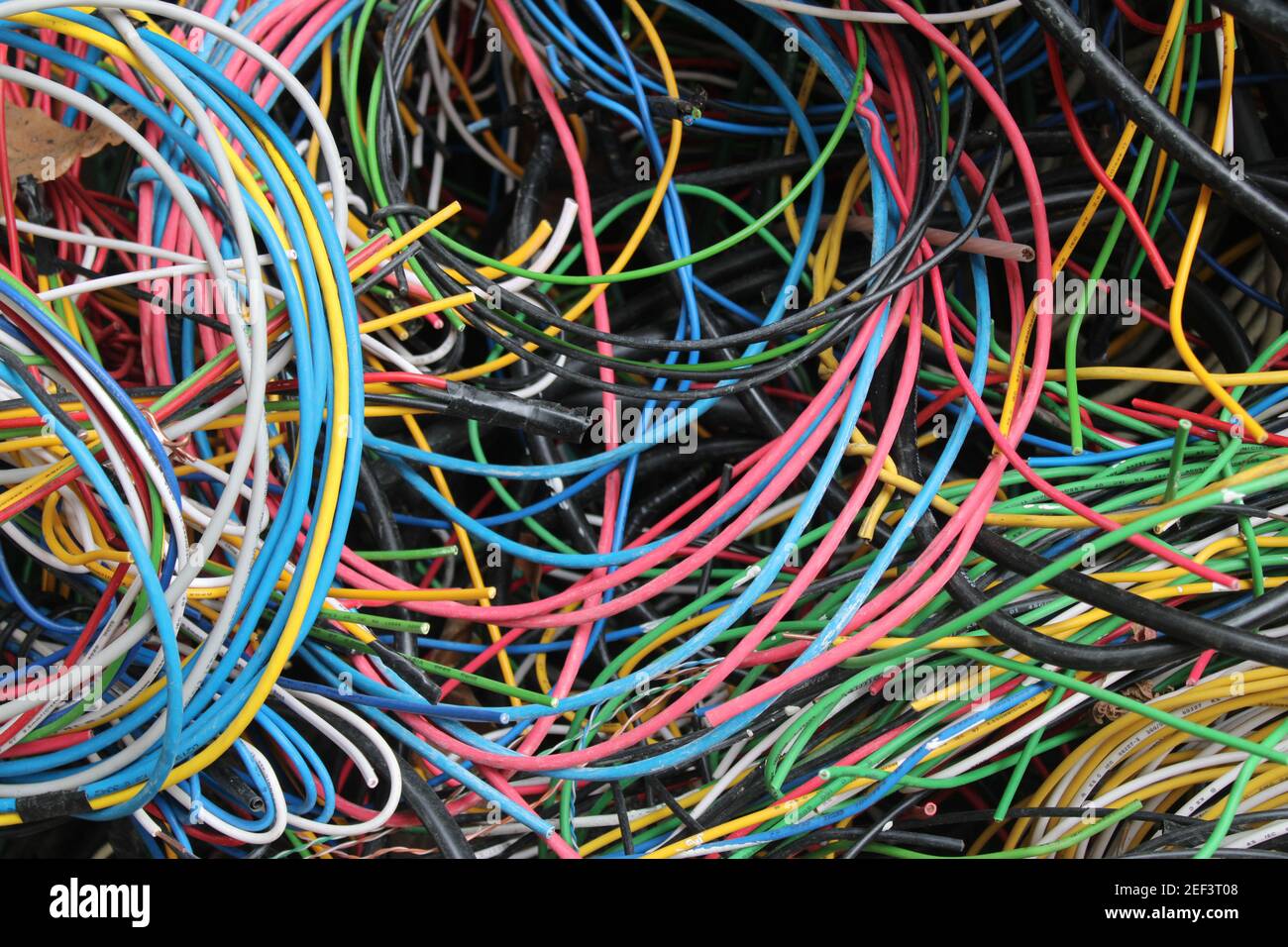 Multicolored wires and cables coiled in a heap behind a local electrician's shop Stock Photo