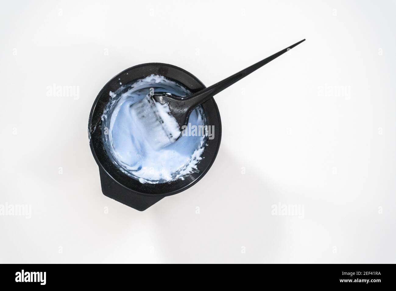 Flat lay. Mixing hair color dye in a black mixing bowl with a brush