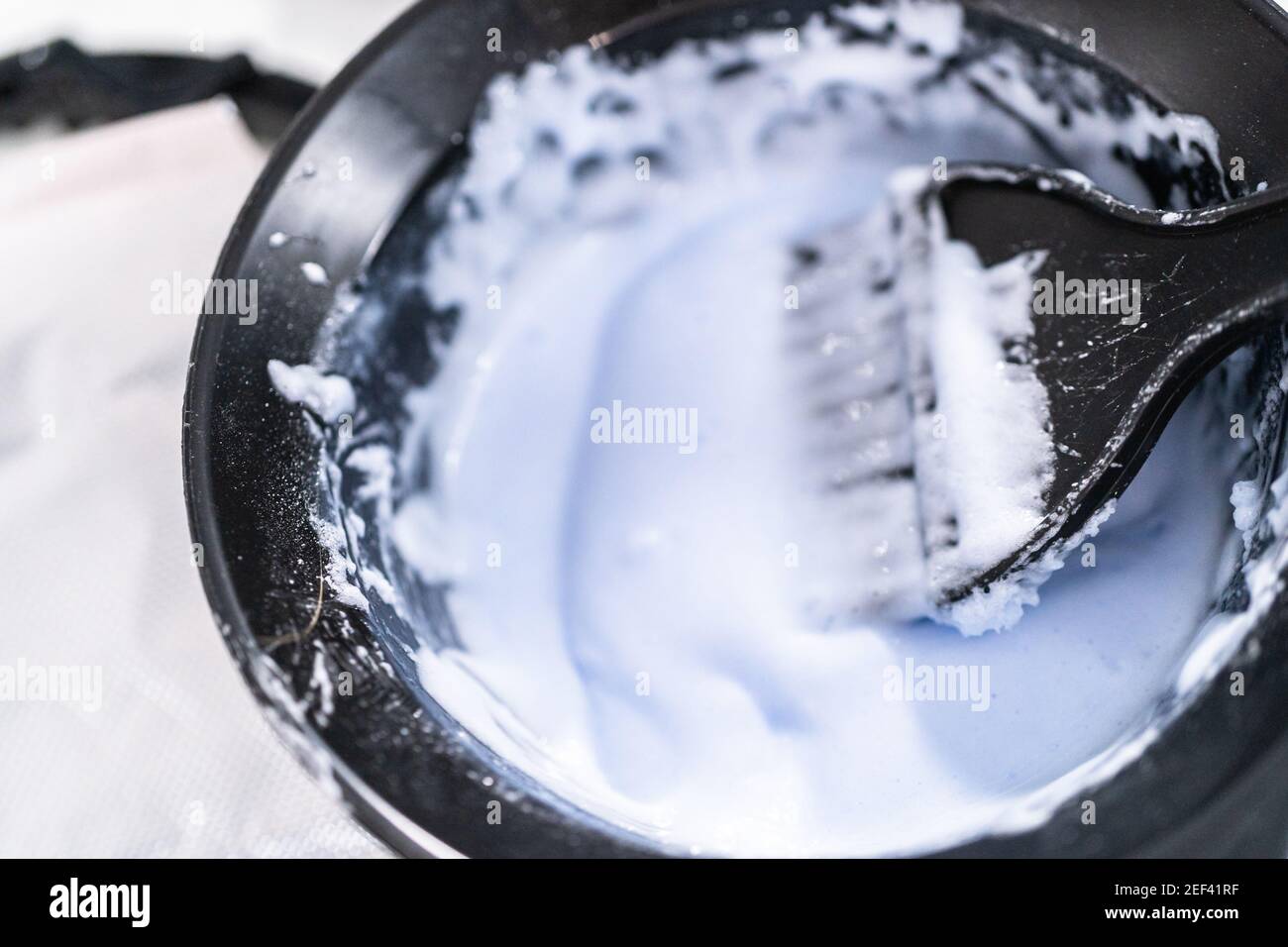 Mixing hair color dye in a black mixing bowl with a brush Stock Photo