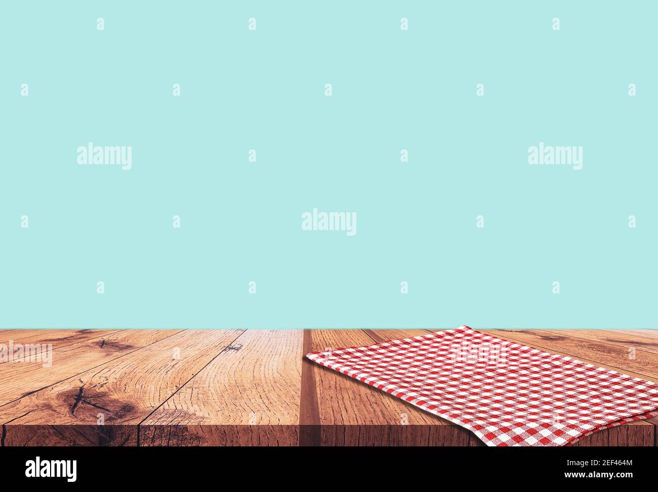 Empty wooden table with red checked tablecloth over blue wall background Stock Photo