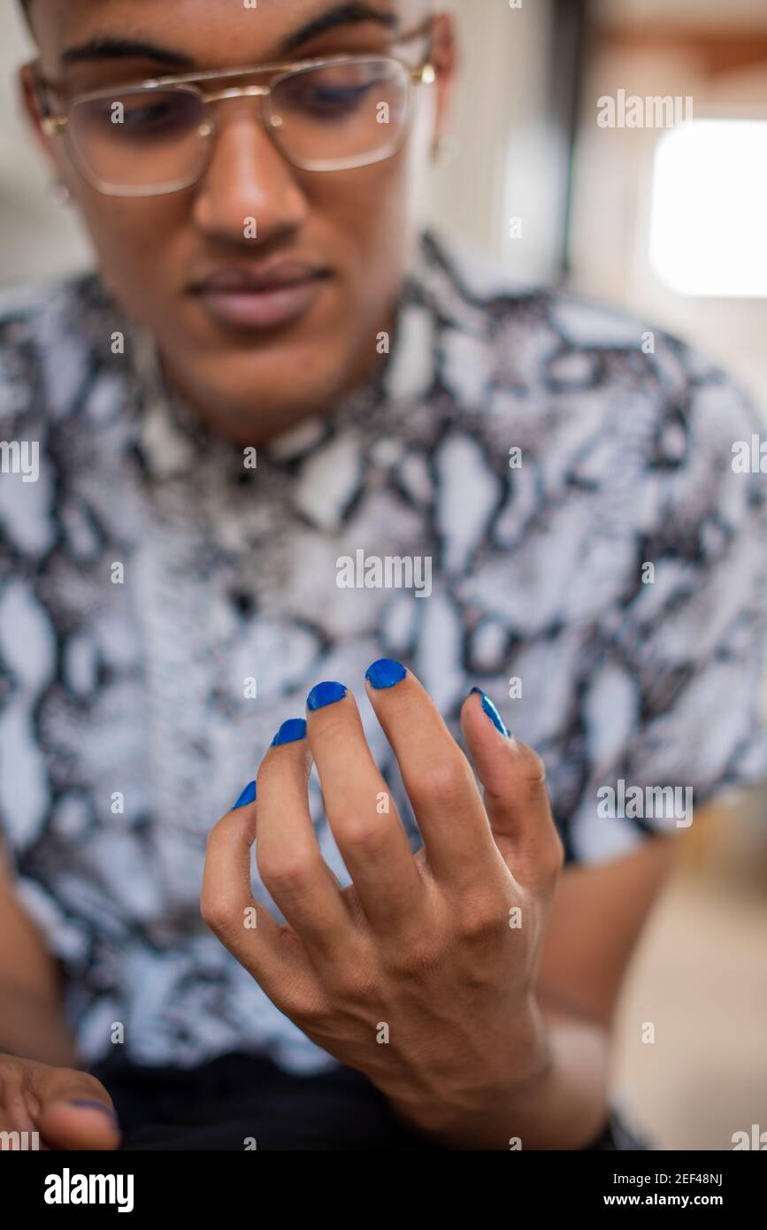 Close up portrait of gender fluid person with colorful blue painted nails Stock Photo