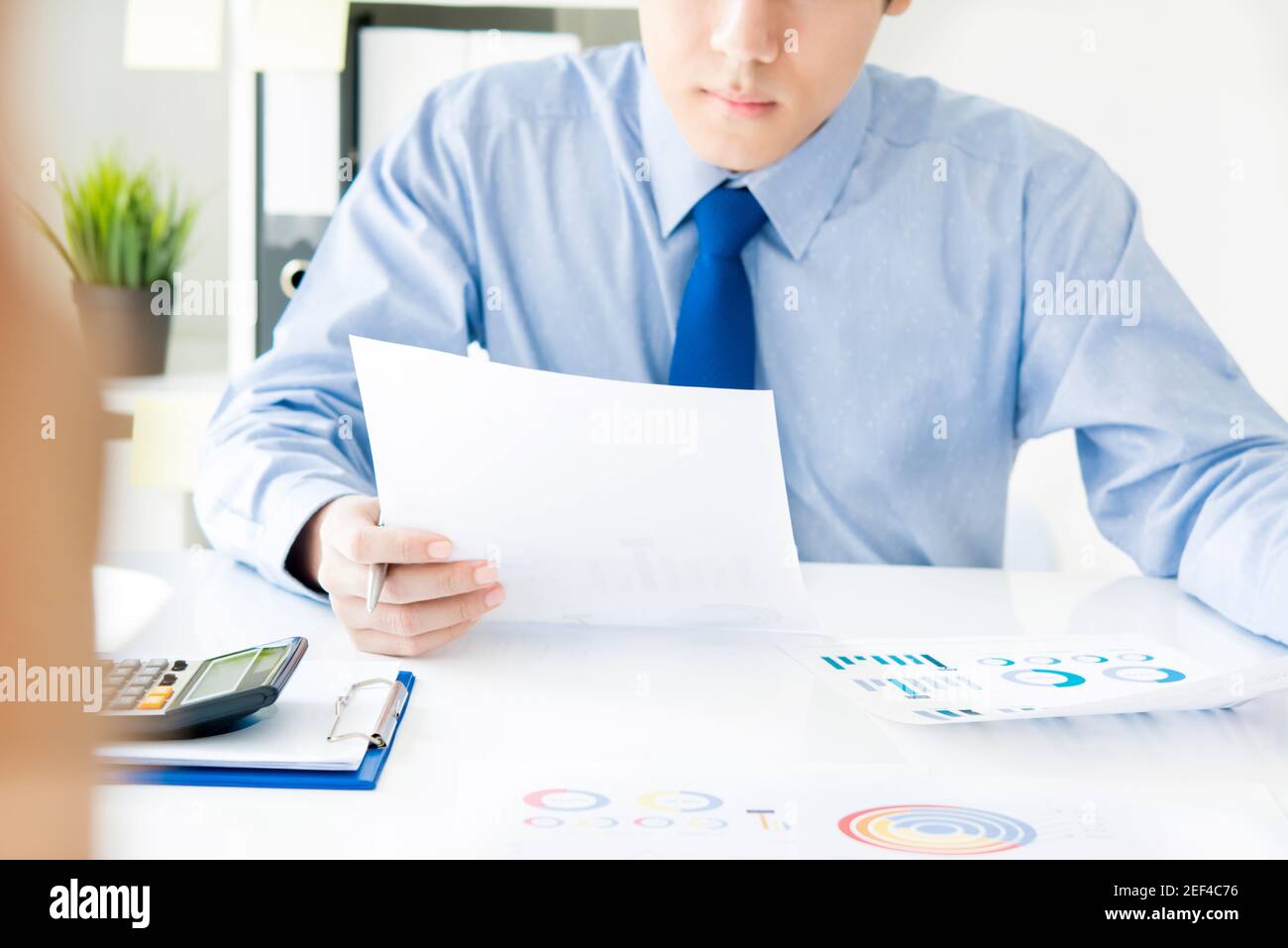 Businessman reading financial data document at working desk in the office Stock Photo