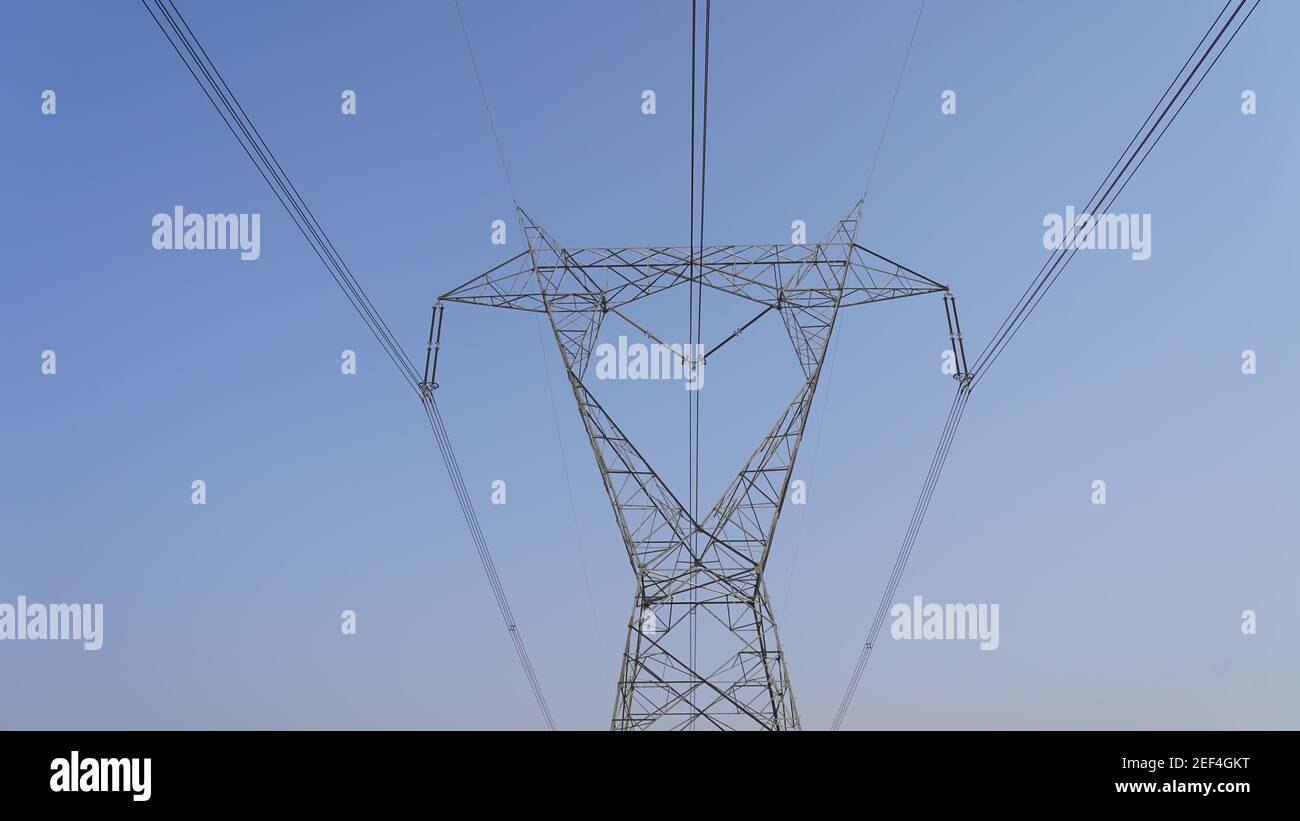 Industrial power supply lines closeup. High voltage electricity through big iron poles. Electricity wires line view. Stock Photo