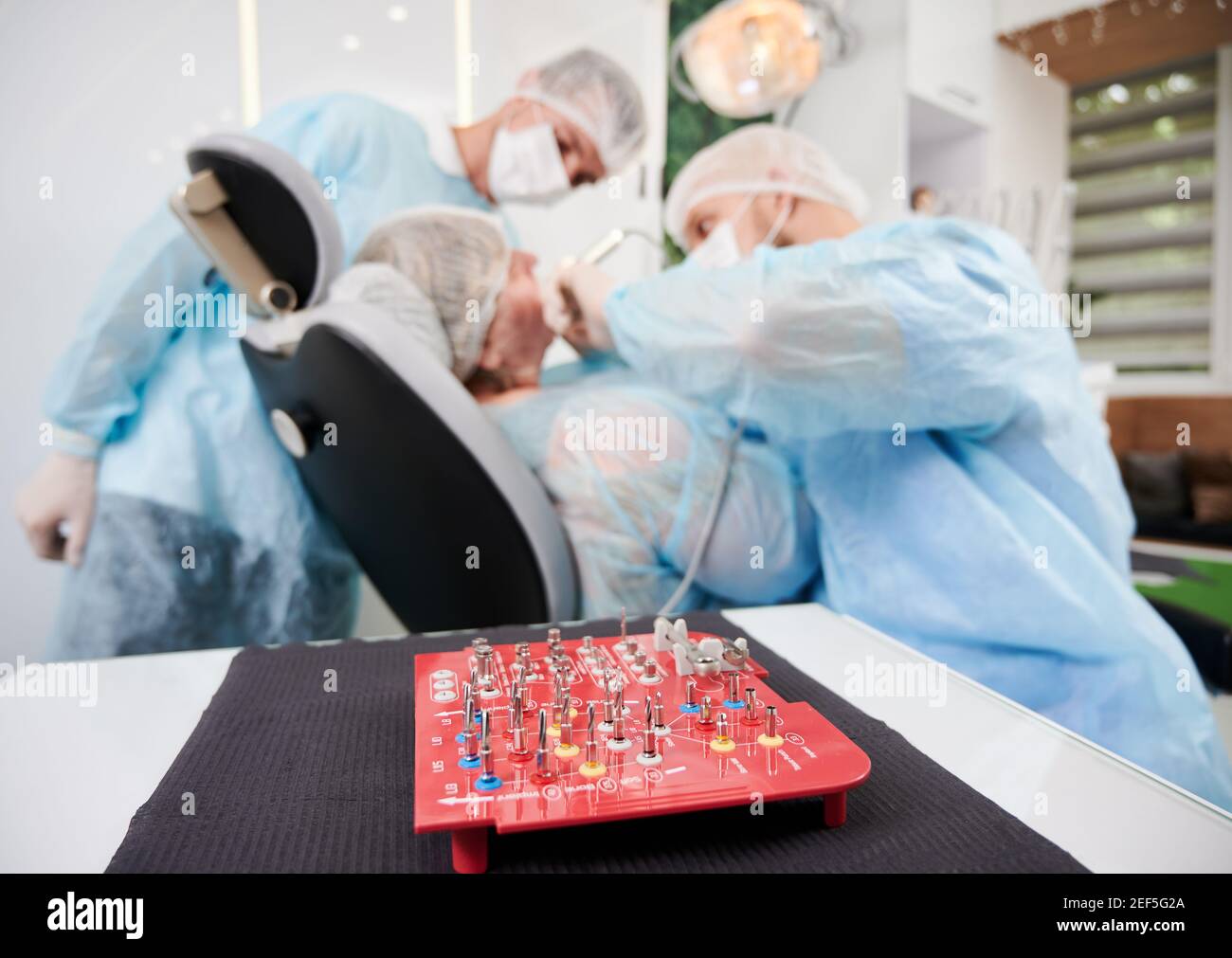 Close up of dental implant surgical kit with doctors and patient on