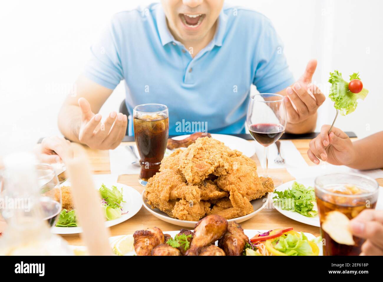 Food and drinks on dining table in front of excited hungry young man Stock Photo