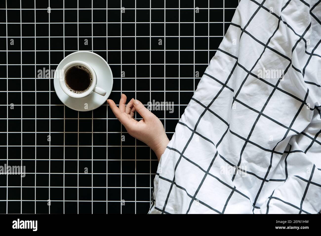 Caffeine and sleep problems. Drinking coffee before bed. A cup of black  coffee on black checkered background Stock Photo - Alamy