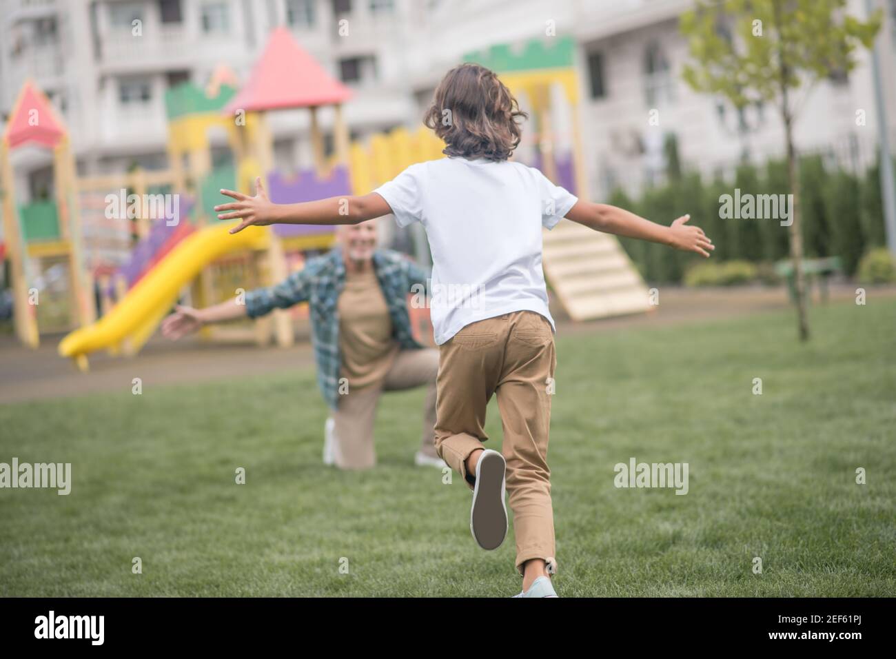 Boy running to his dads open arms and looking happy Stock Photo
