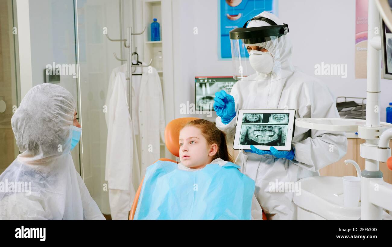 Dentist with face shield explaining panoramic mouth xray image to
