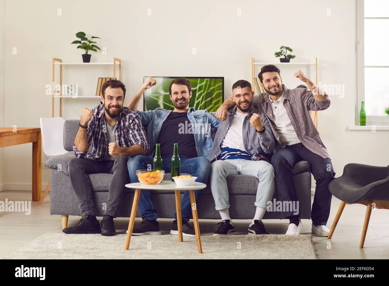 Smiling excited men friends expressing power and success during beer and snack party Stock Photo