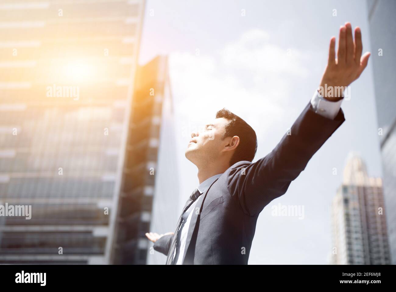 Happy businessman raising his arms, open palms, with face looking up ...
