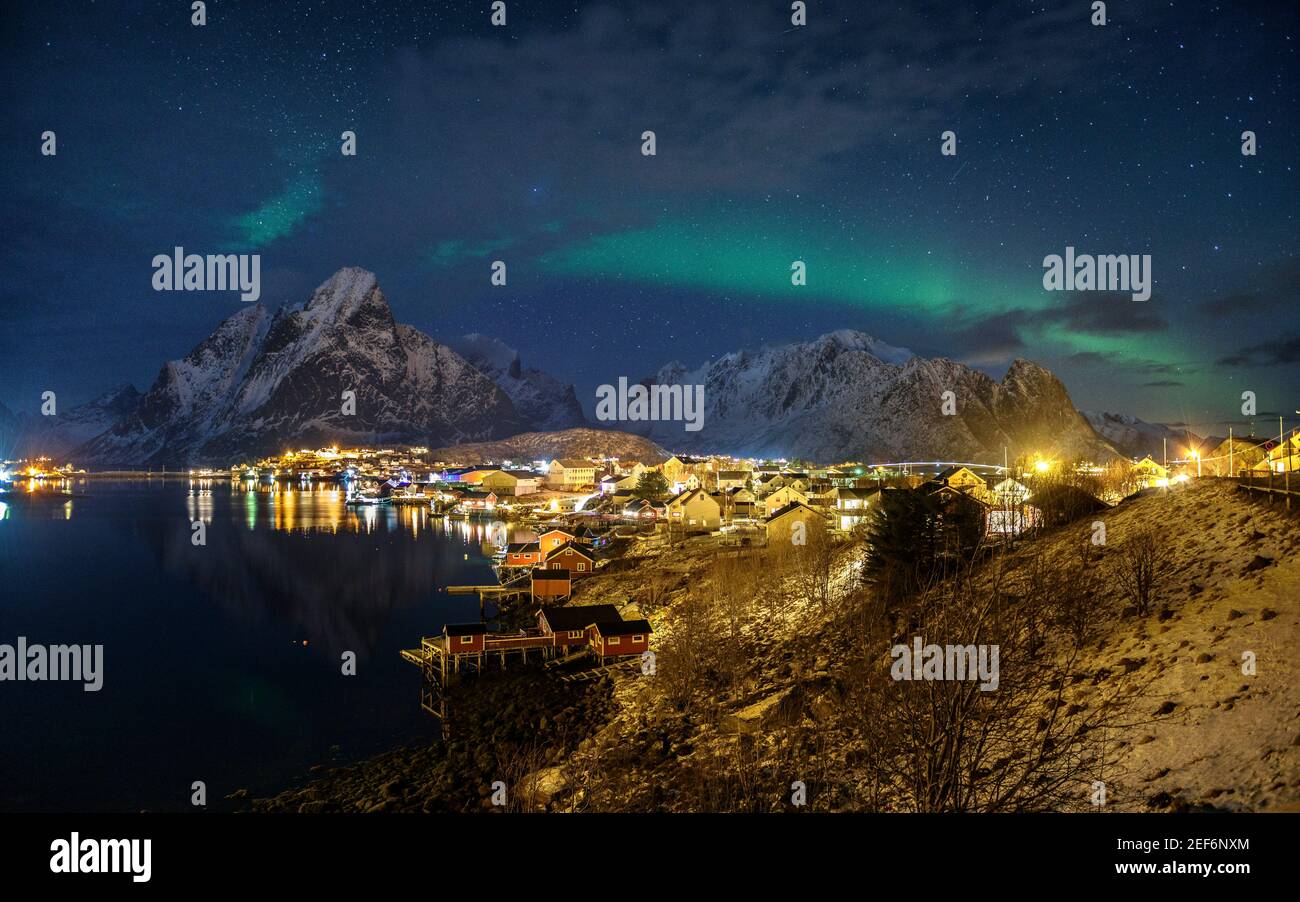 Winter northern lights in Reinefjorden and the village of Reine (Lofoten, Norway) Stock Photo
