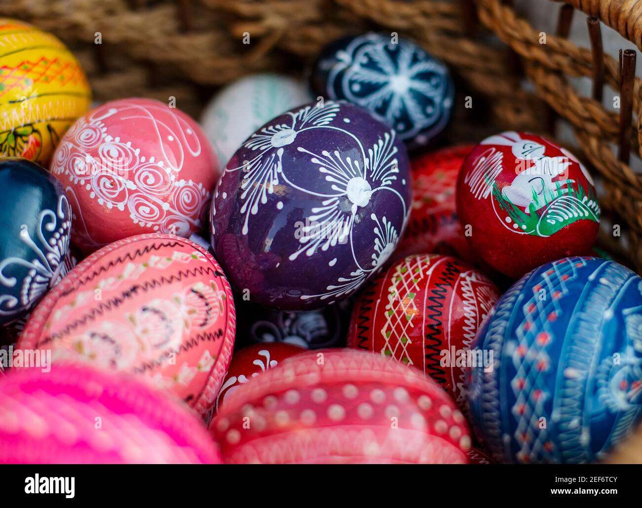 Many colorful decorated easter eggs in wicker basket Stock Photo