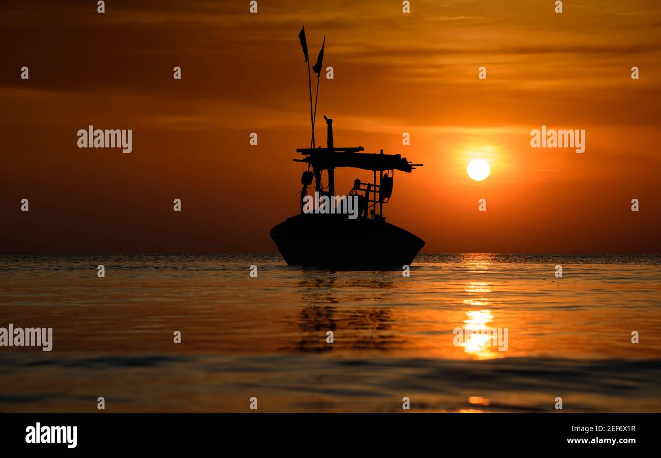 Silhouette fishery boats in the sea with sunset warm low lighting and ...