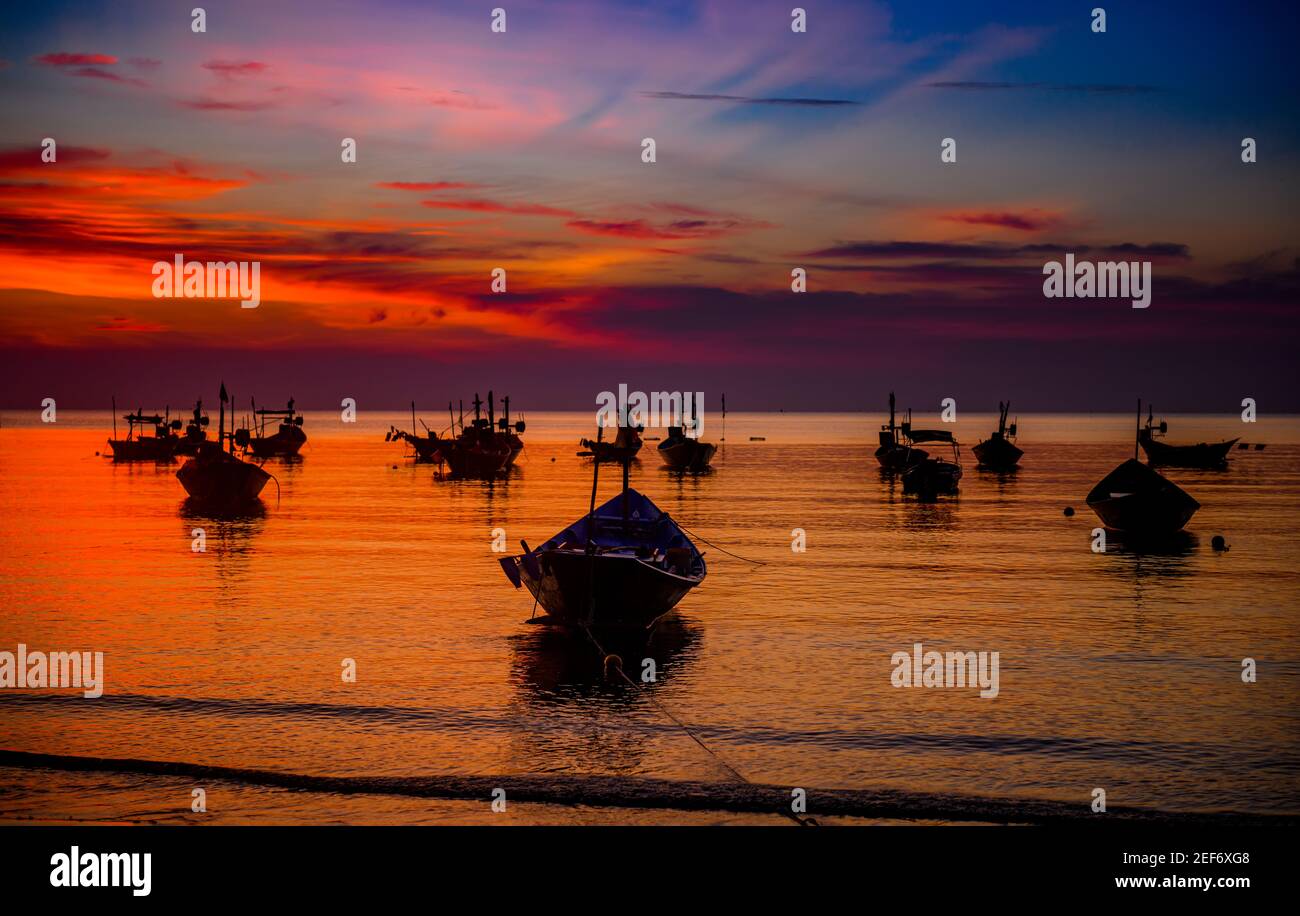 Silhouette fishery boats in the sea with sunset warm low lighting and ...