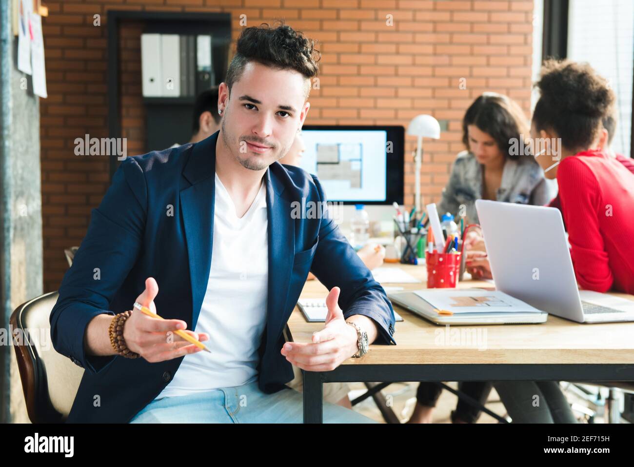 Hispanic casual businessman in meeting room of  interior design company with multiethnic colleagues Stock Photo