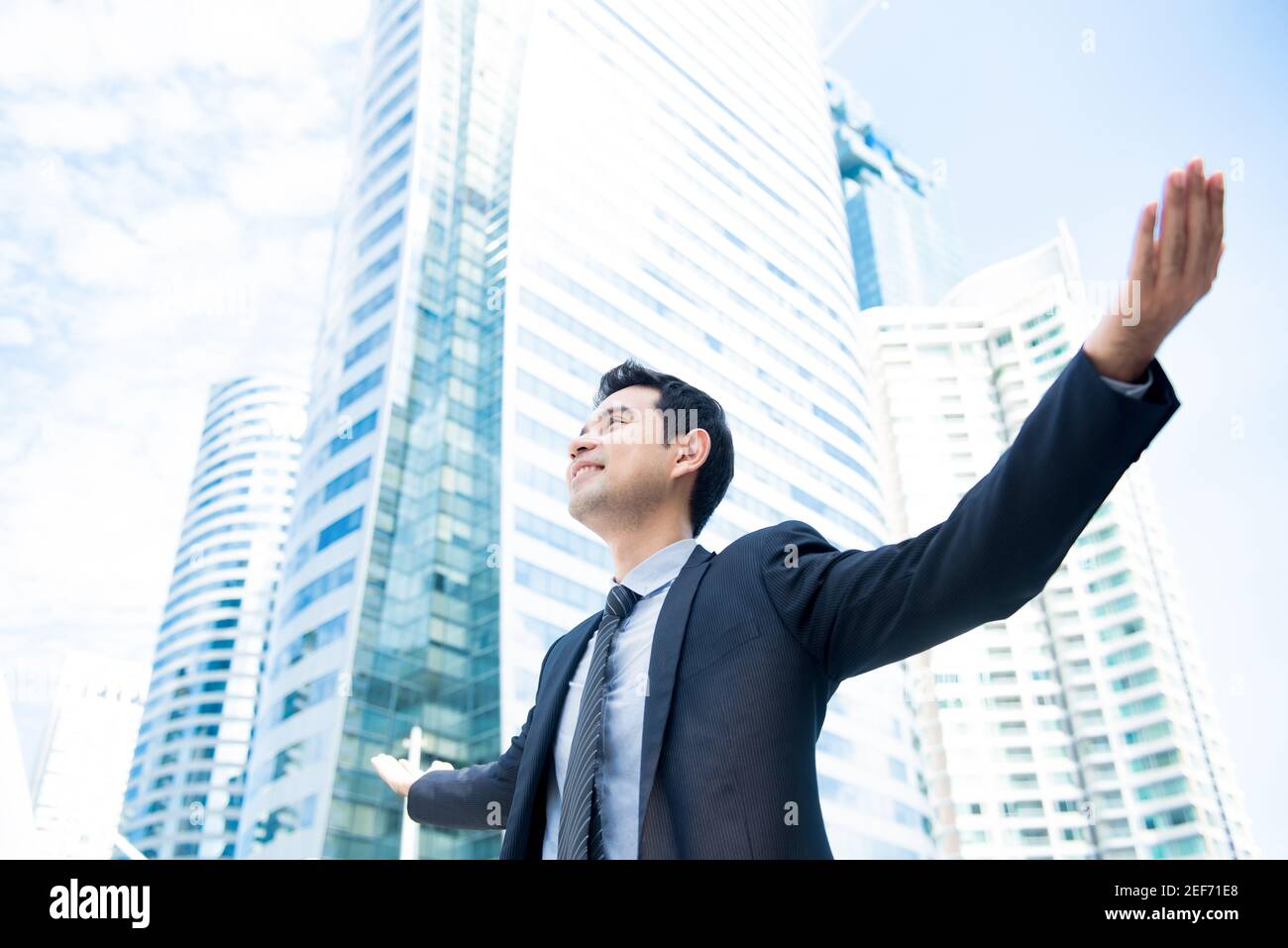 Businessman raising his arms opening palms with face looking up, in ...