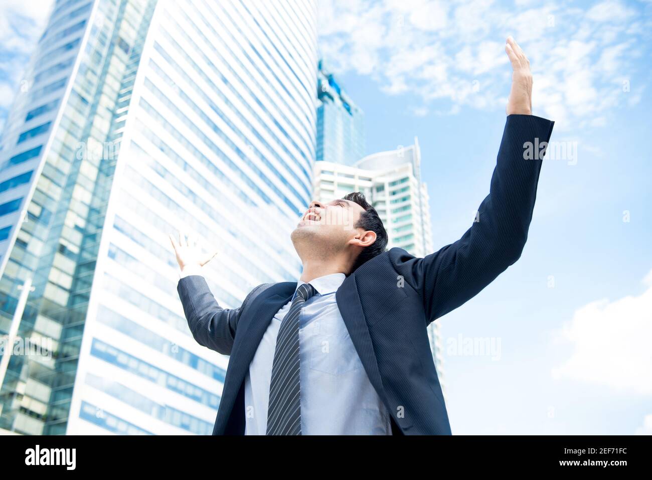 Businessman raising his arms opening palms with face looking up, in ...