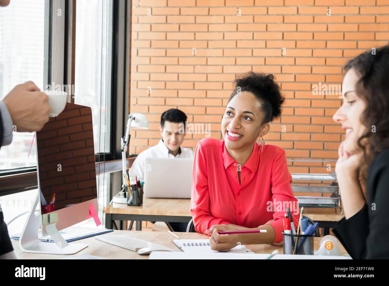 Friendly black businesswoman in co-working space with multiethnic colleagues Stock Photo