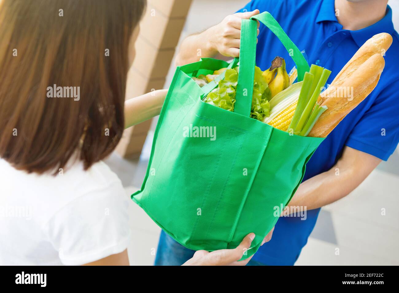 Delivery man giving grocery bag to a woman food shopping service
